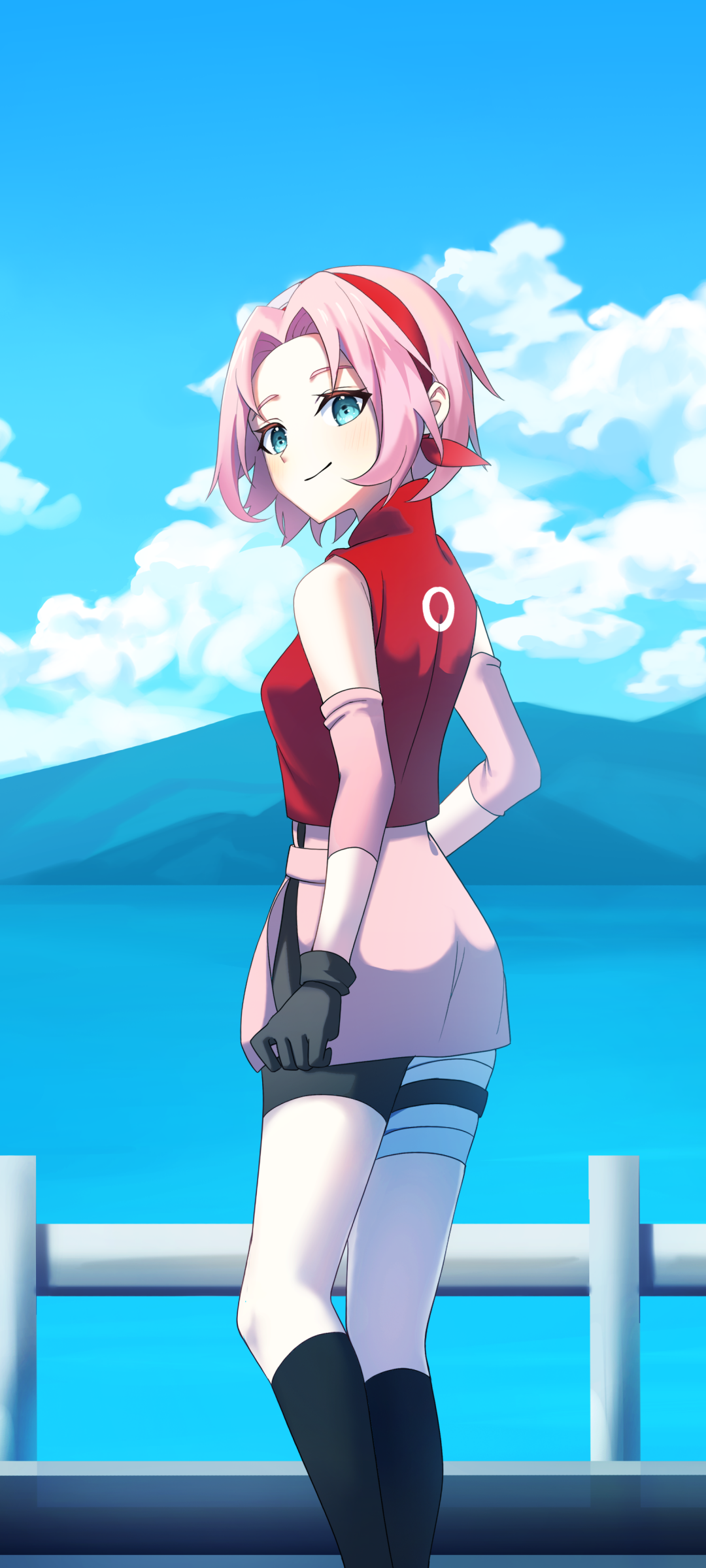 Phone wallpaper — Sakura from Naruto: pink-haired kunoichi in a red sleeveless outfit stands by a seaside railing, looking back beneath a bright blue sky and distant mountains.