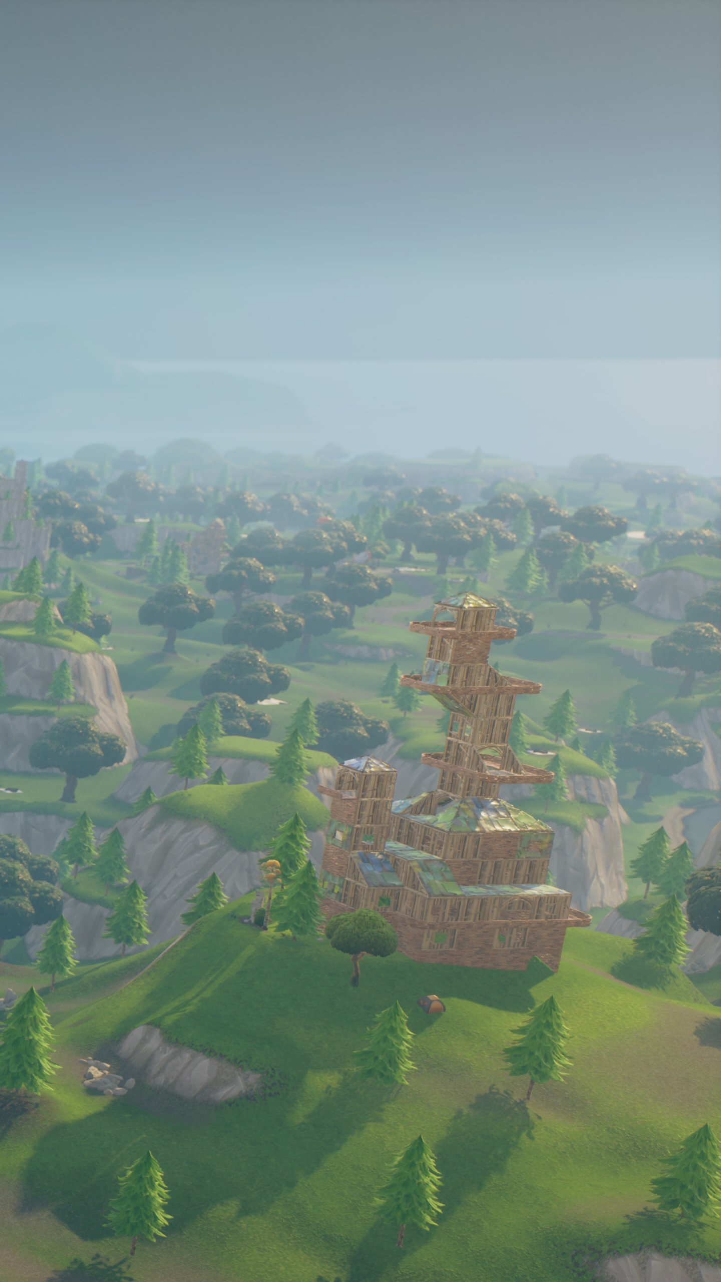 Video game Fortnite phone wallpaper showing an aerial view of green hills, scattered trees and wooden structures rising from an island beneath a hazy sky.