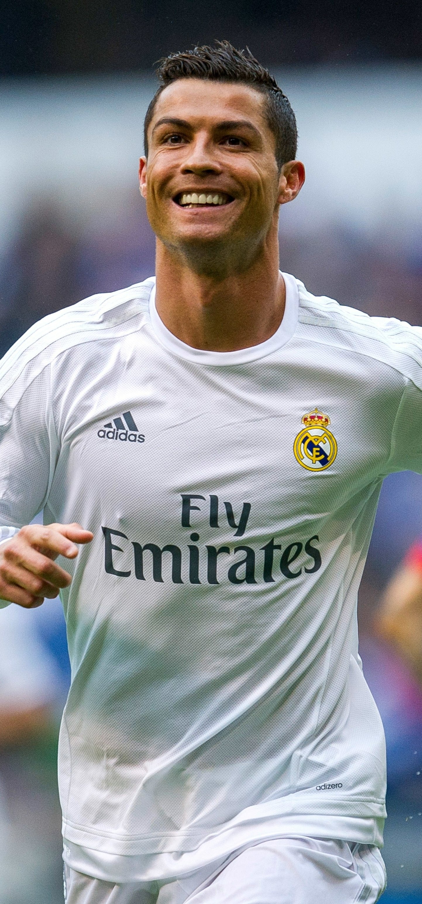Cristiano Ronaldo smiling in a white Real Madrid jersey during a match, captured as a vibrant phone wallpaper for iPhones and Android devices.