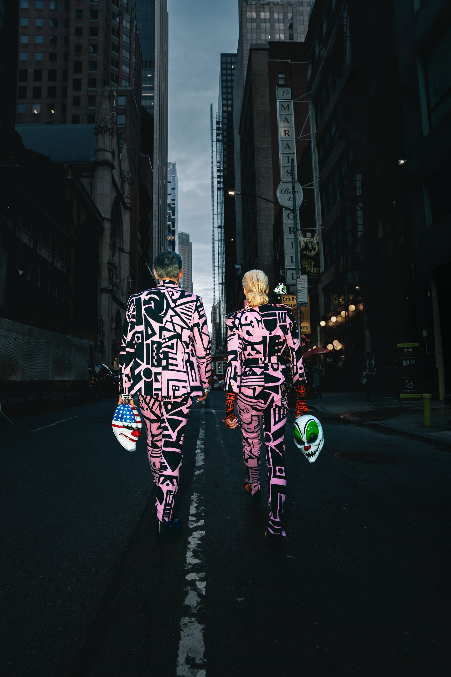 Payday 3 themed phone wallpaper featuring two characters in neon-lit suits walking through a city street at dusk.