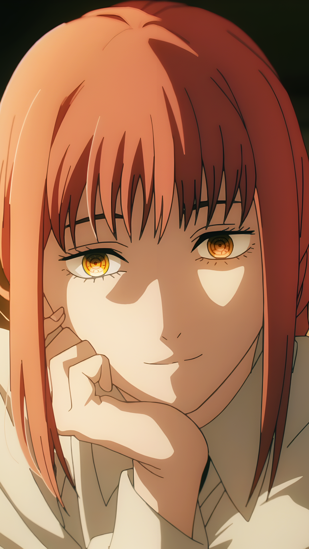 Phone wallpaper: close-up of Makima from the anime Chainsaw Man, warm light on her orange hair and golden eyes, resting chin on hand with a subtle, knowing smile.
