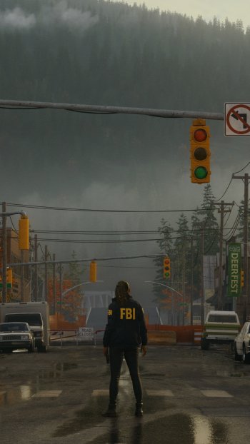 Alan Wake 2 themed phone wallpaper featuring an FBI agent standing in a rainy street with a backdrop of misty forests and traffic lights.