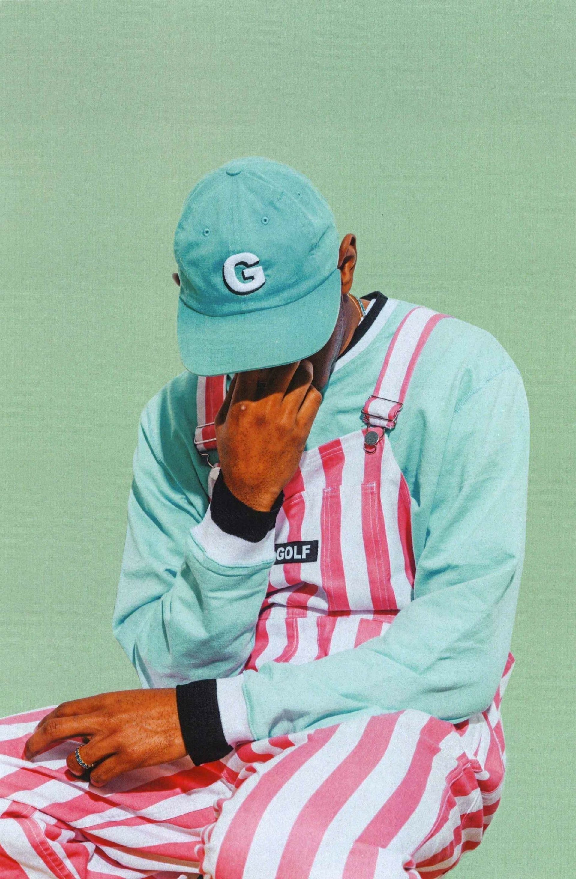A vibrant phone wallpaper featuring rapper Tyler the Creator, dressed in mint green and pink stripes, reflecting his unique style and artistic flair.