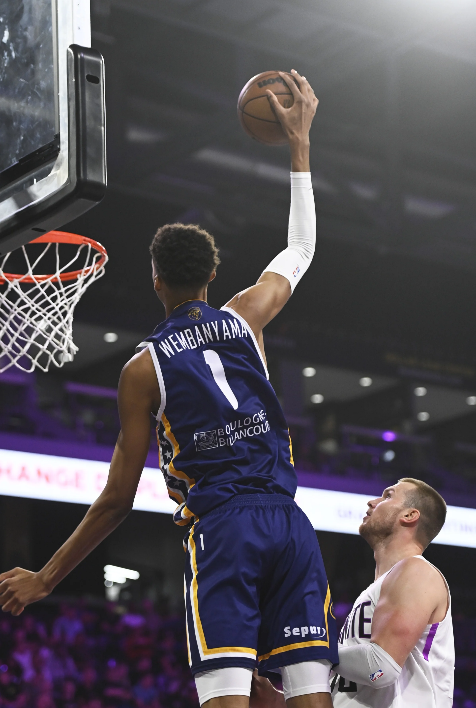 Victor Wembanyama soaring for a dunk during an NBA game, showcasing his impressive skills. A dynamic basketball phone wallpaper celebrating athleticism and sport.