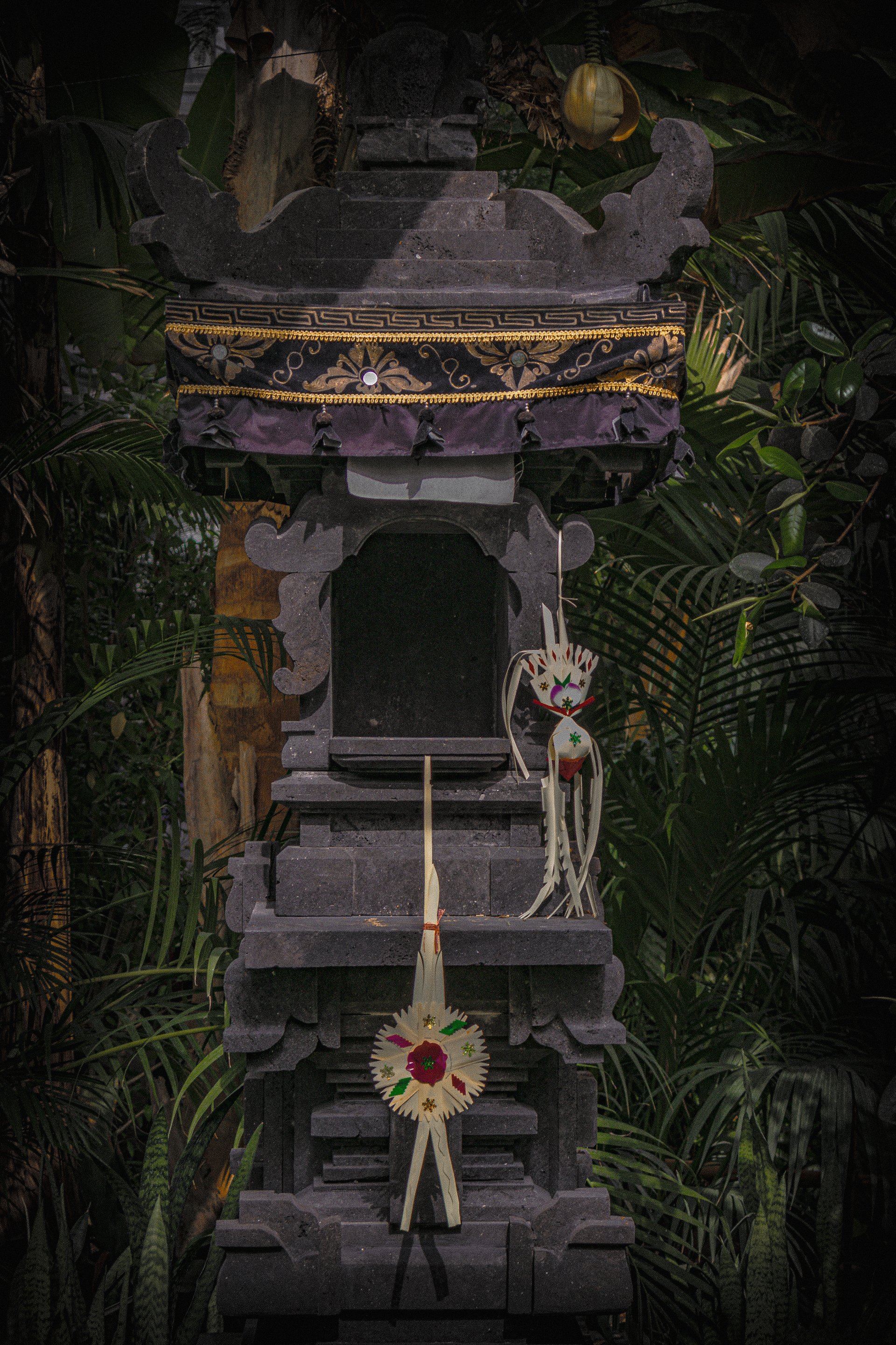 Chill photography of a traditional stone shrine adorned with intricate decorations, nestled among lush tropical foliage, designed as a phone wallpaper for iPhones and Android.