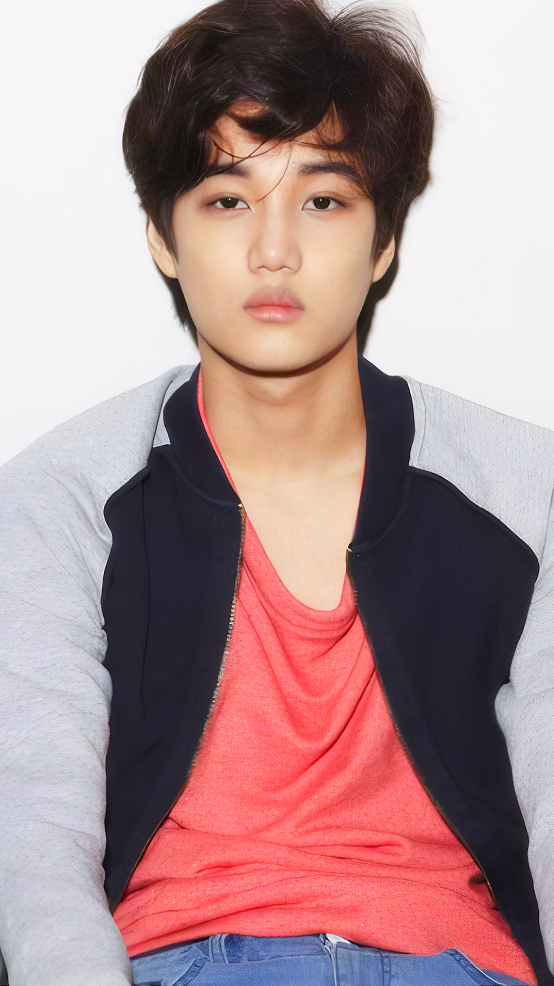 Phone wallpaper featuring EXO's Kai from the Mama photoshoot, posing against a plain white background, wearing a black and gray jacket over a red shirt.