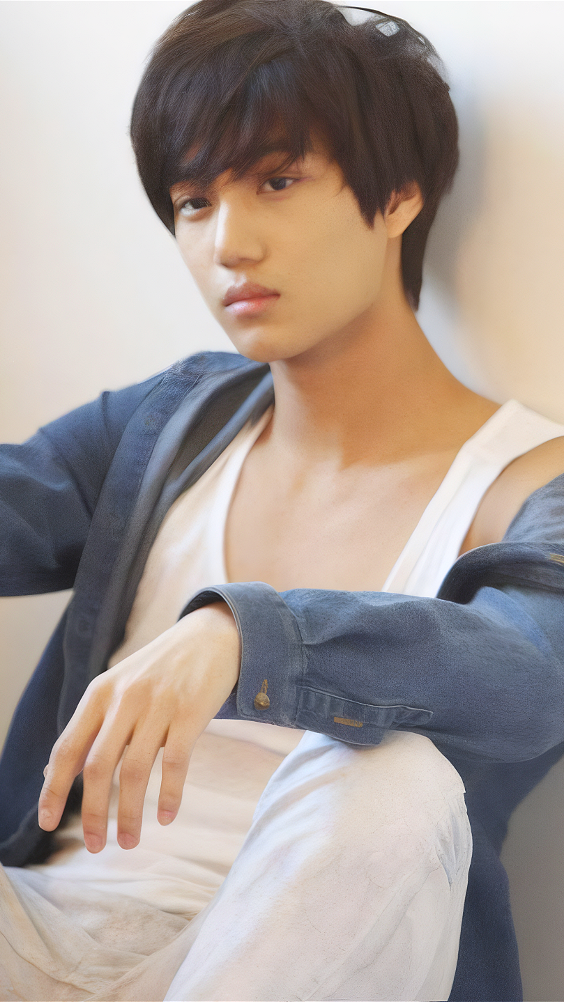 Phone wallpaper featuring EXO's Kai from the Mama photoshoot, showcasing a relaxed pose with soft lighting on an iPhone or Android display.