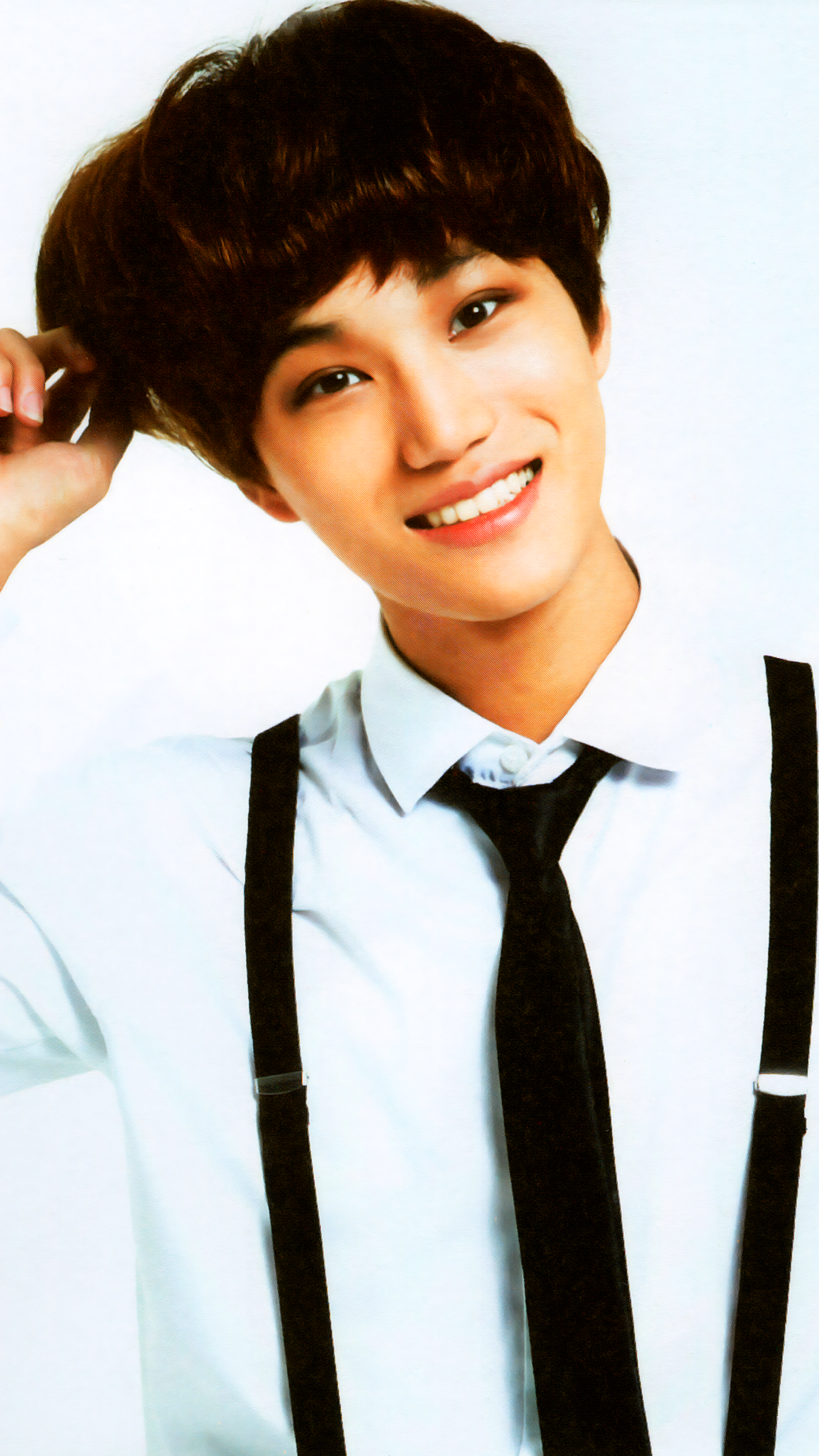 Phone wallpaper featuring EXO's Kai from the Miracles in December photoshoot, smiling in a white shirt with black suspenders and tie, bright against a white background.