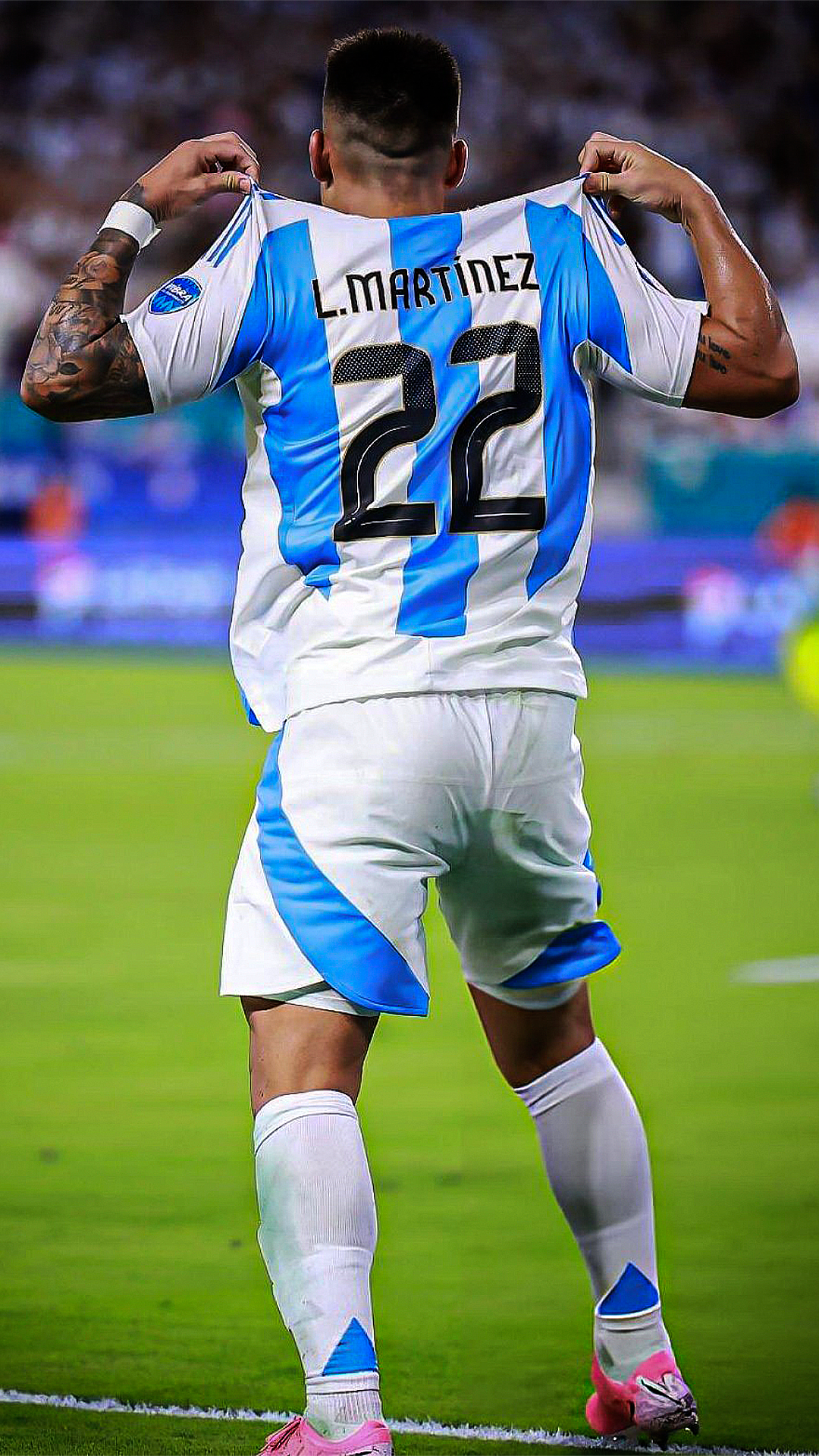 Phone wallpaper of Lautaro Martínez from Argentina National Football Team, showing him from behind holding his jersey with number 22 during a soccer match.