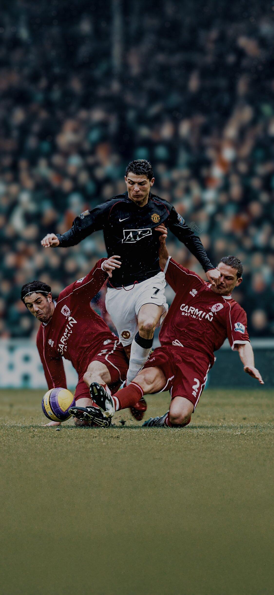 Cristiano Ronaldo, wearing Manchester United F.C. colors, skillfully maneuvers past two opponents during a dynamic soccer match. A striking phone wallpaper for fans.