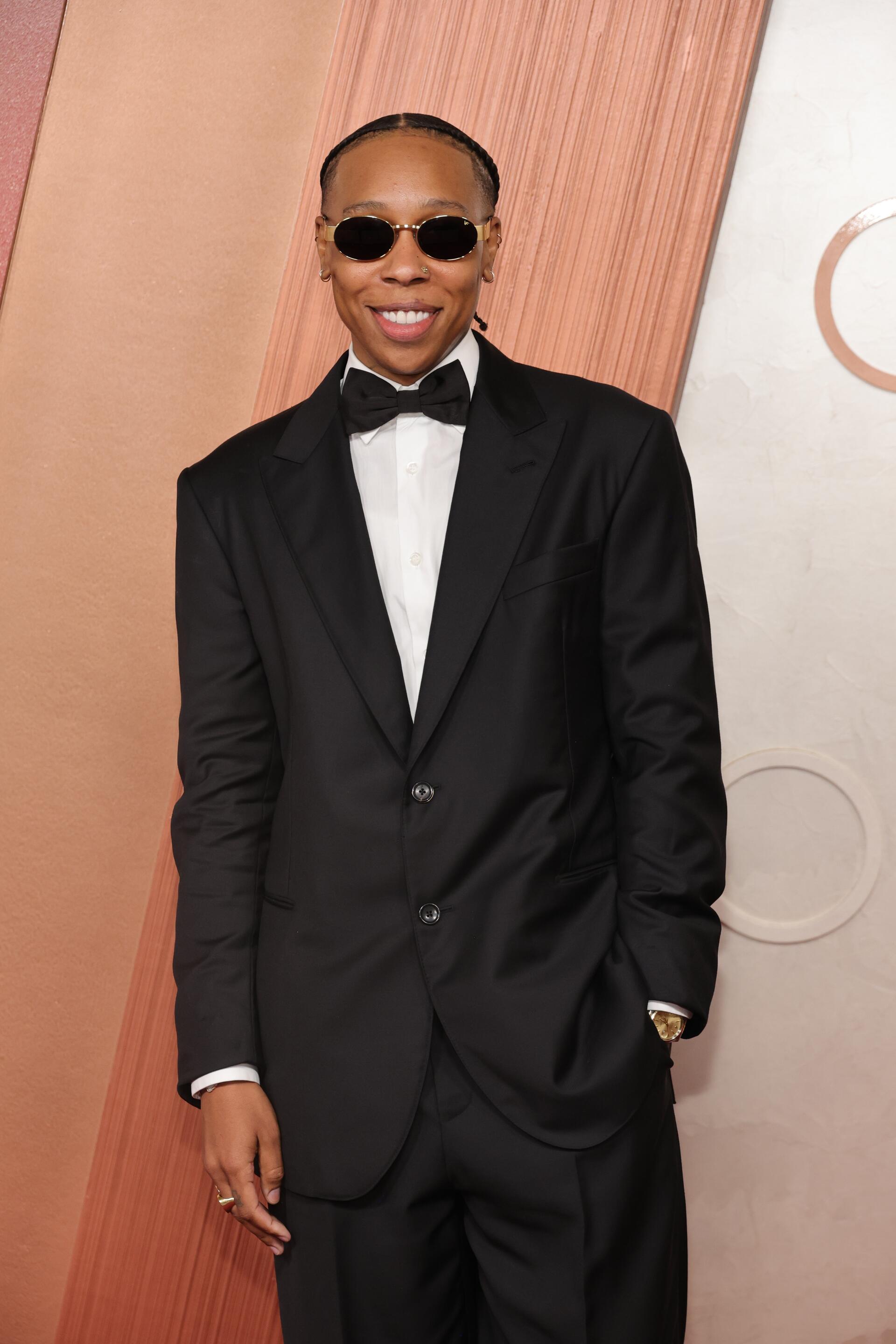 Lena Waithe poses confidently at the Academy Awards (Oscars), wearing a sleek black tuxedo and sunglasses against a stylish backdrop, making a striking phone wallpaper.