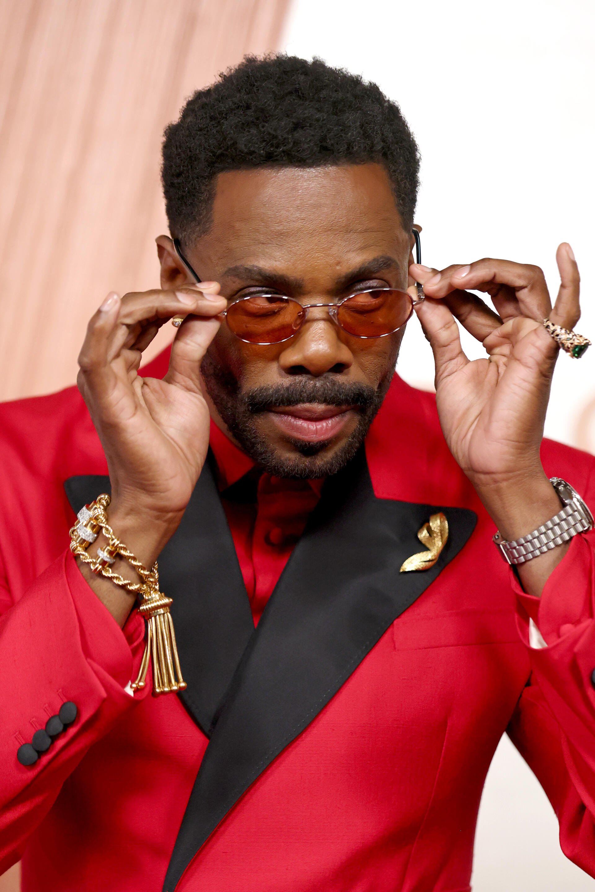 Colman Domingo adjusts his stylish sunglasses while wearing a vibrant red suit at the Academy Awards, capturing a moment of elegance and confidence. A striking phone wallpaper choice.