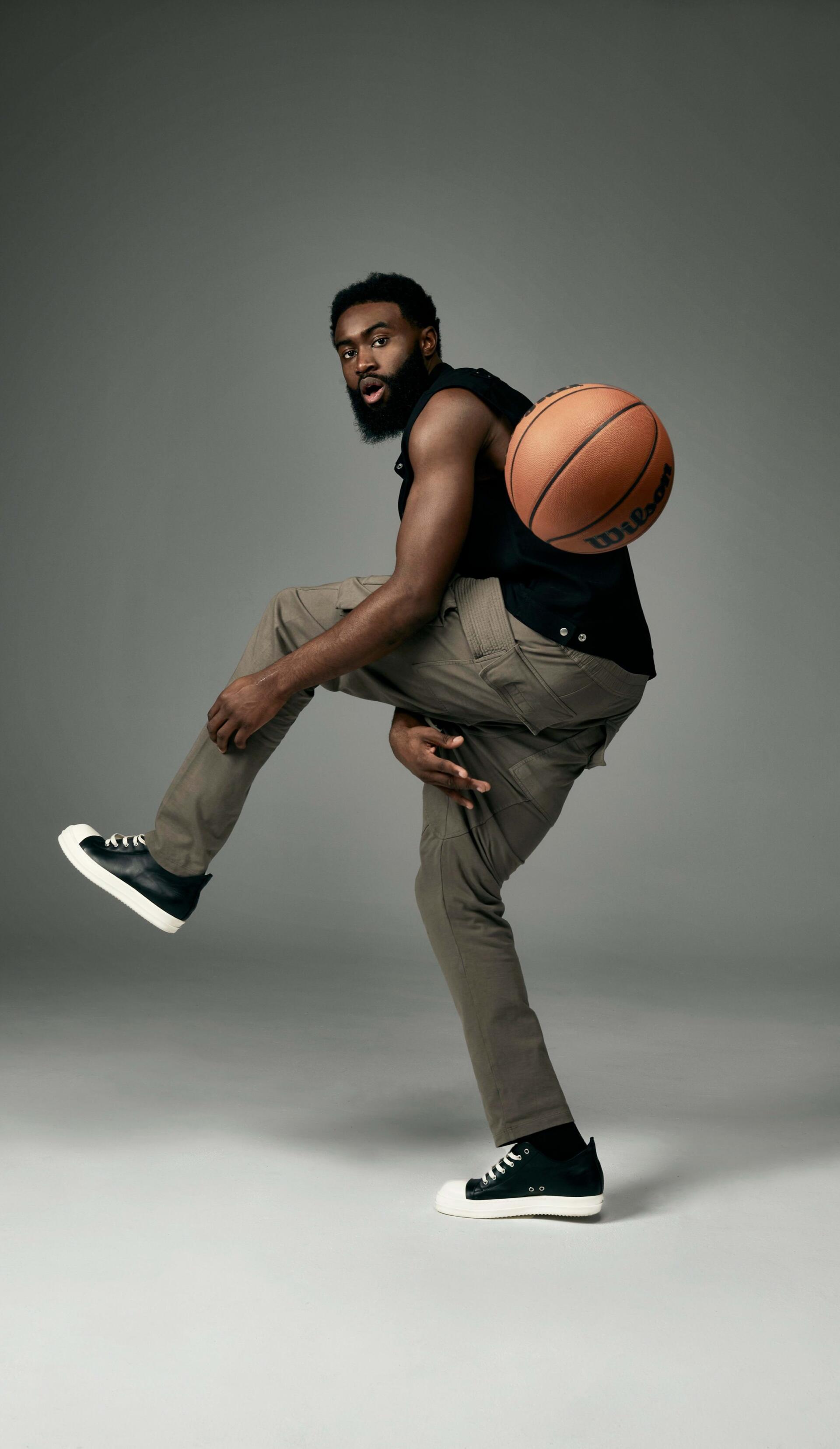Phone wallpaper image of NBA player Jaylen Brown in motion, balancing a basketball, designed for iPhone and Android displays.