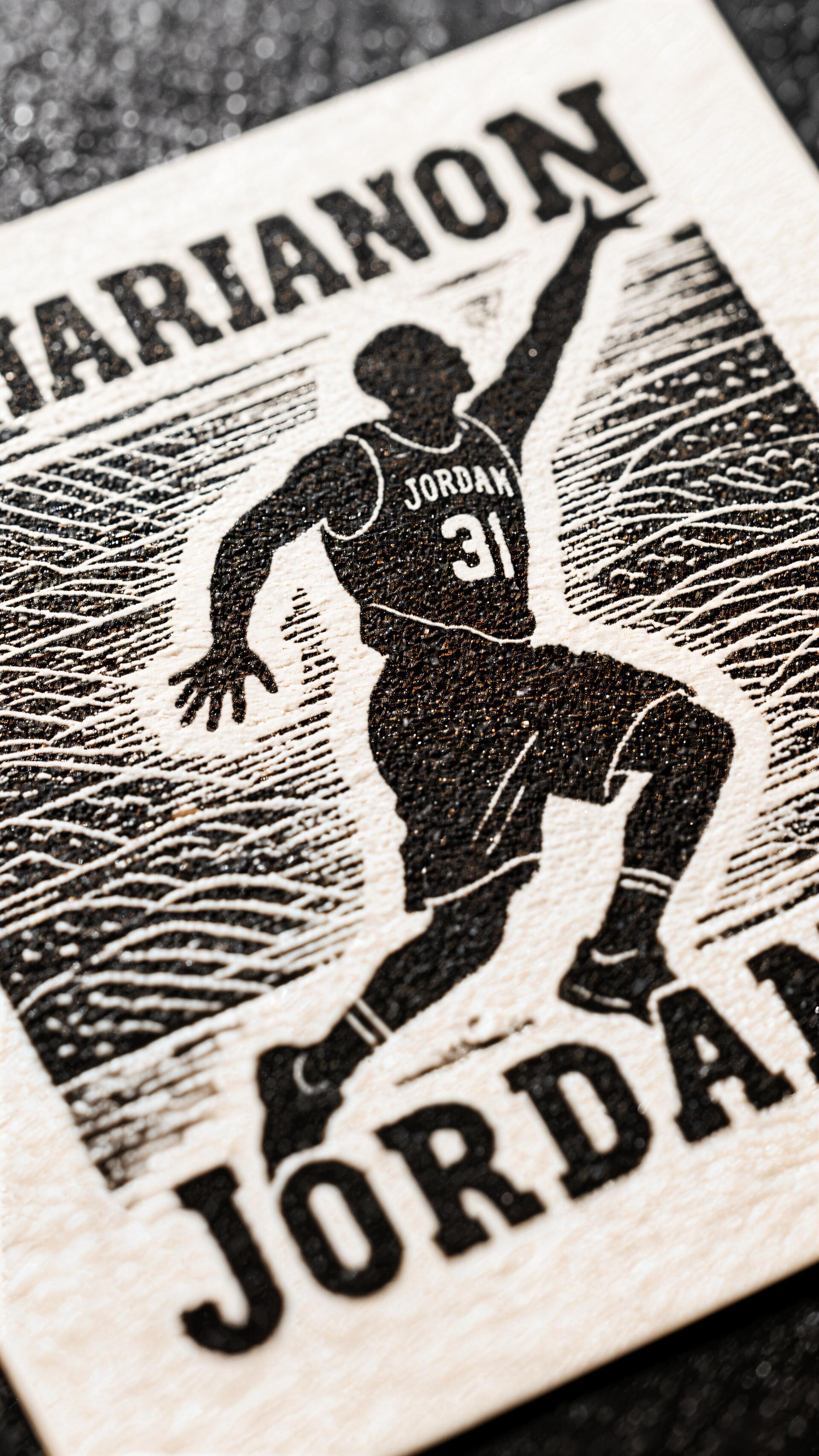Phone wallpaper featuring a stylized black-and-white silhouette of basketball player Michael Jordan in mid-air, with bold text displaying JORDAN and MARANON. Compatible with iPhone and Android.