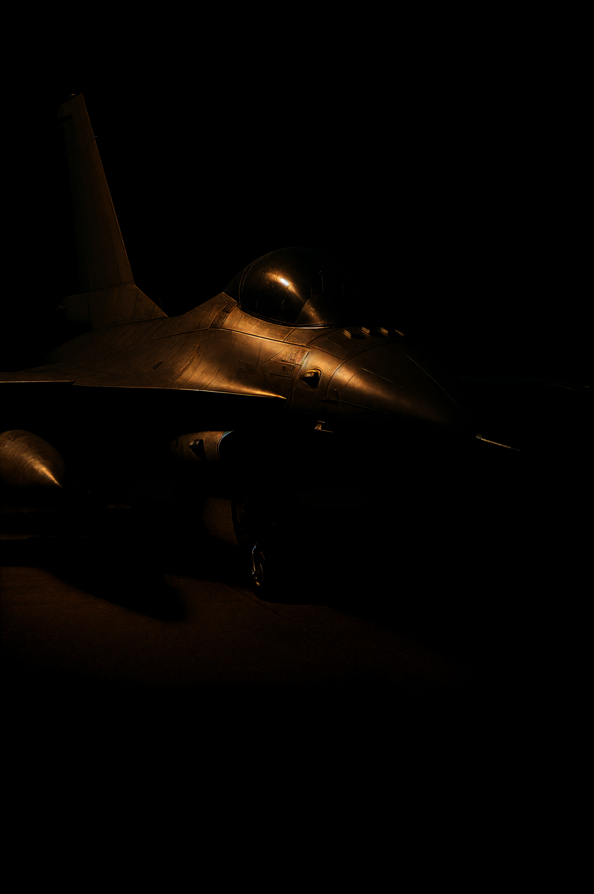 Jet fighter illuminated in low light, creating a dramatic and sleek phone wallpaper for iPhone and Android devices.