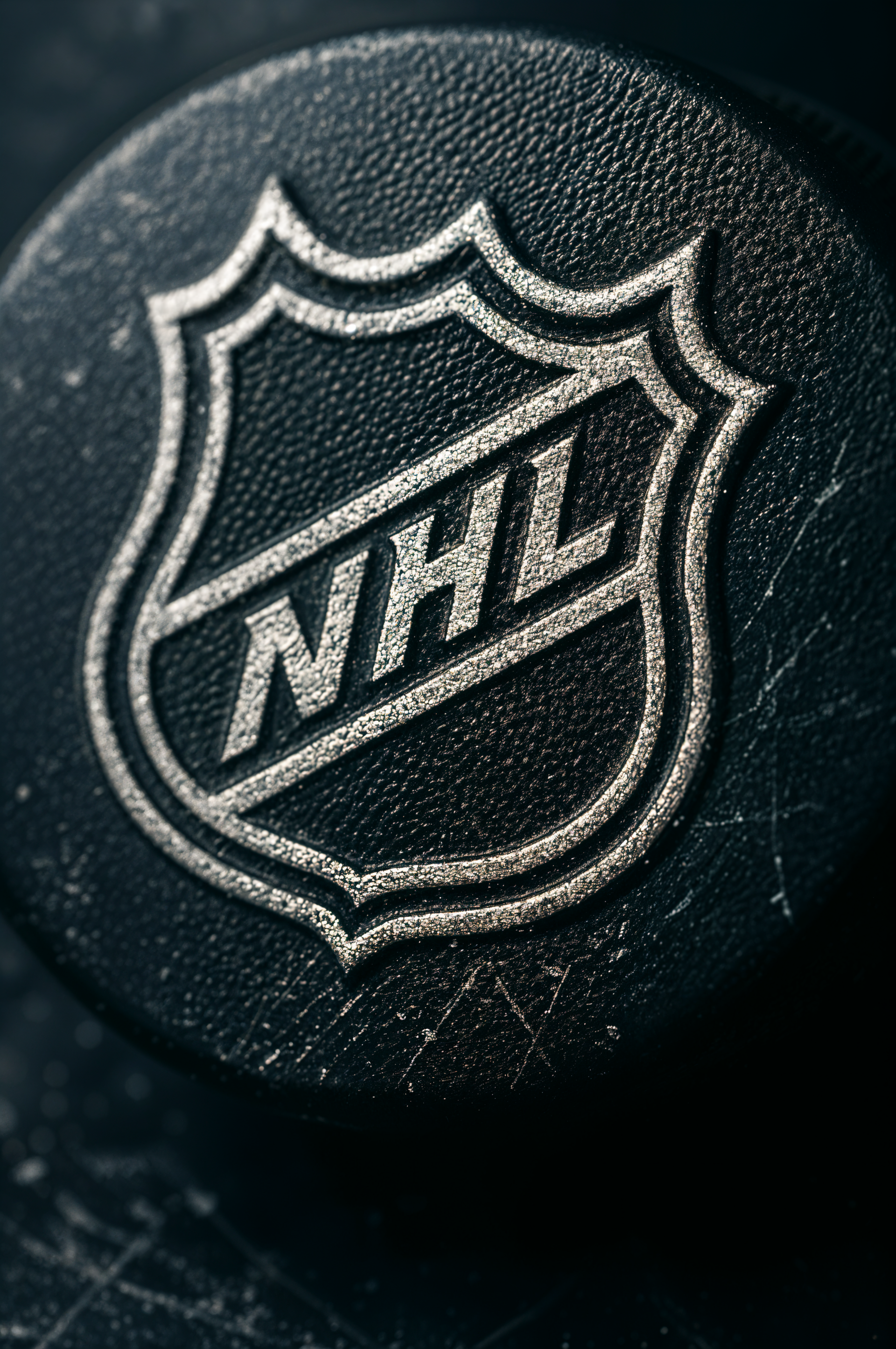 Vertical phone wallpaper showing a close-up of a scuffed black hockey puck embossed with the NHL shield logo on a scratched surface.
