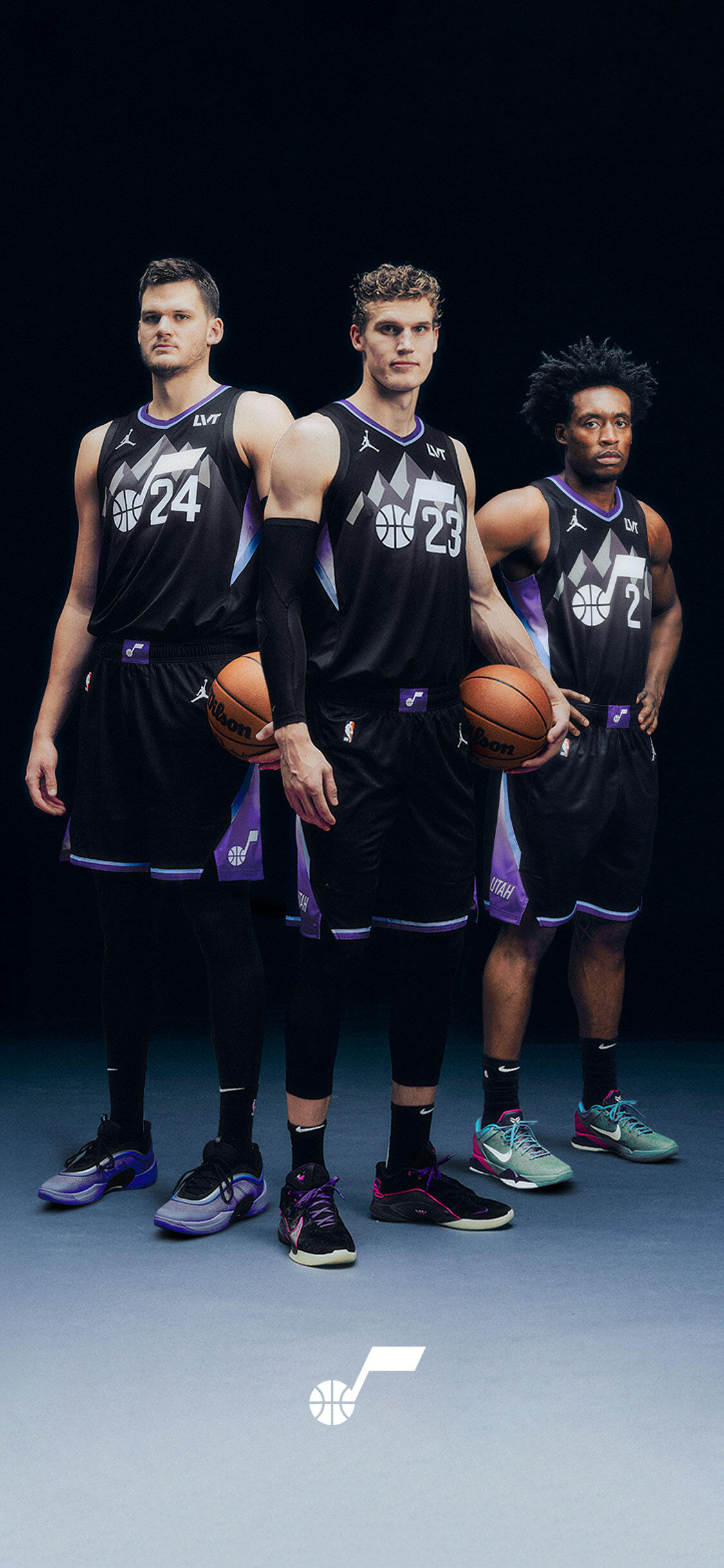 Phone wallpaper of three NBA Utah Jazz players in black jerseys holding basketballs in a studio pose, with the Utah Jazz logo at the bottom.