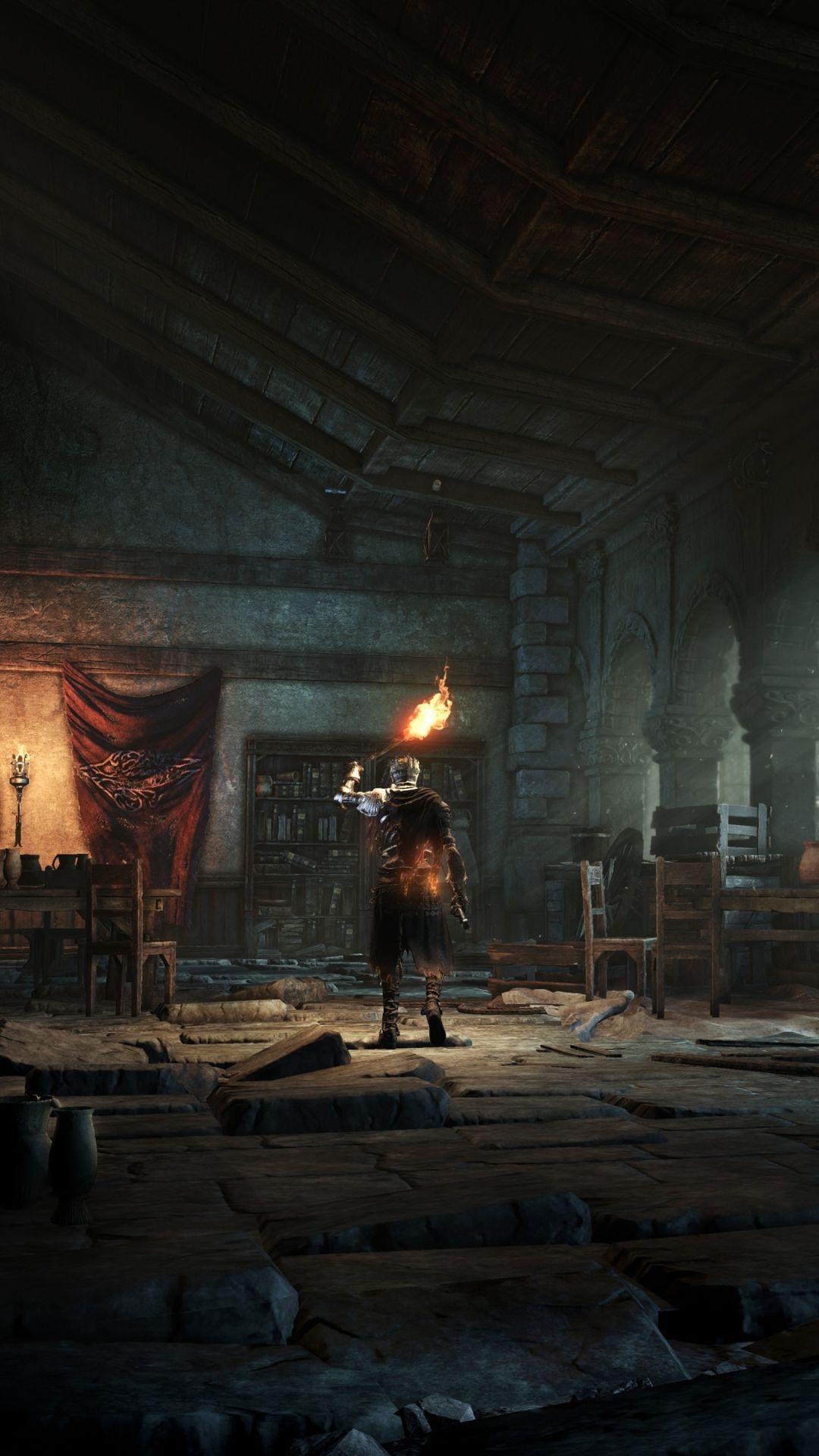 Dark Souls video game phone wallpaper: lone armored figure holds a torch in a ruined stone hall, warm light piercing deep shadow.