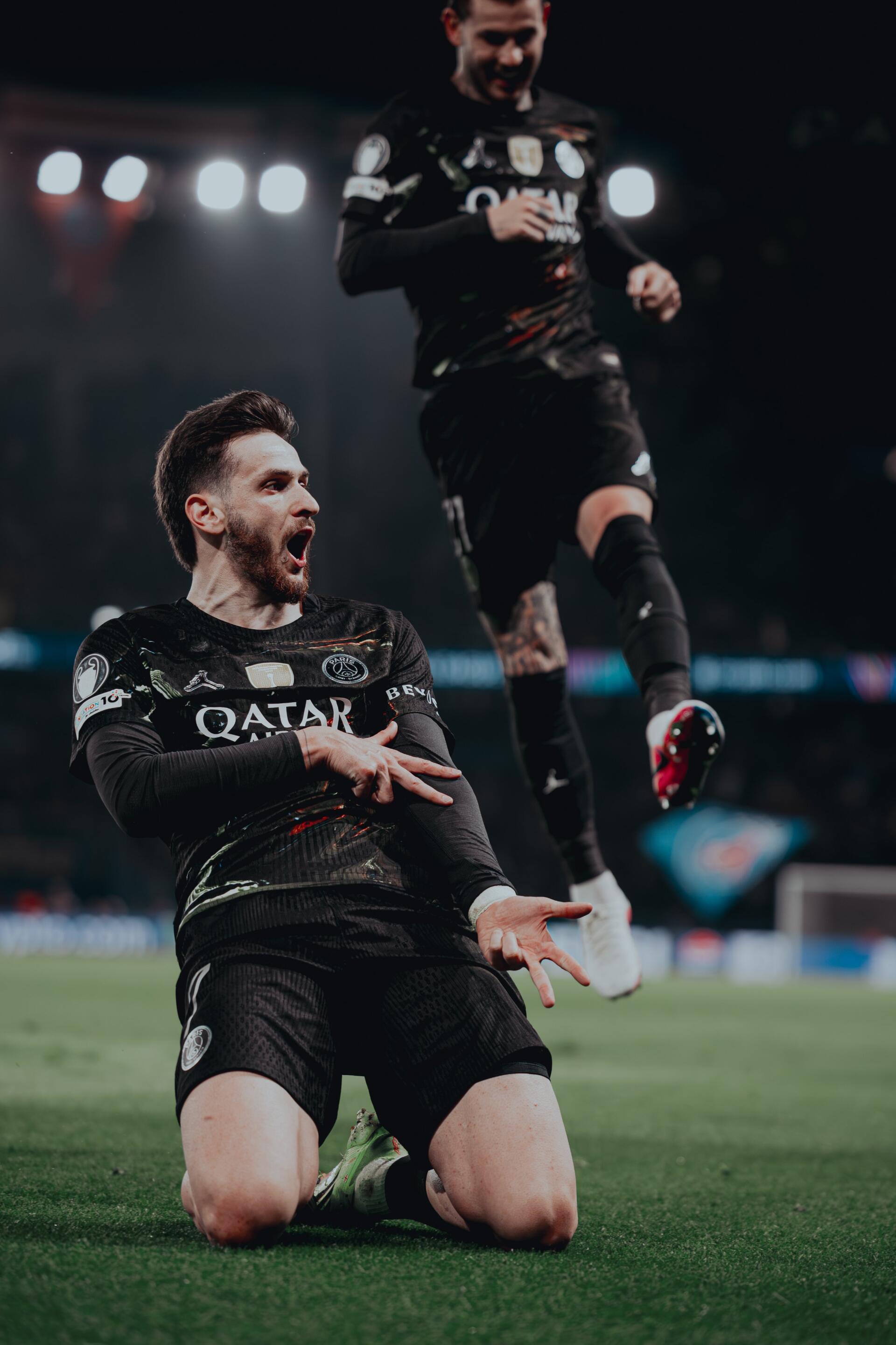 Phone wallpaper of a Paris Saint-Germain F.C. player sliding in celebration on a floodlit pitch, high-energy soccer sports moment. I can’t identify or name people in images.