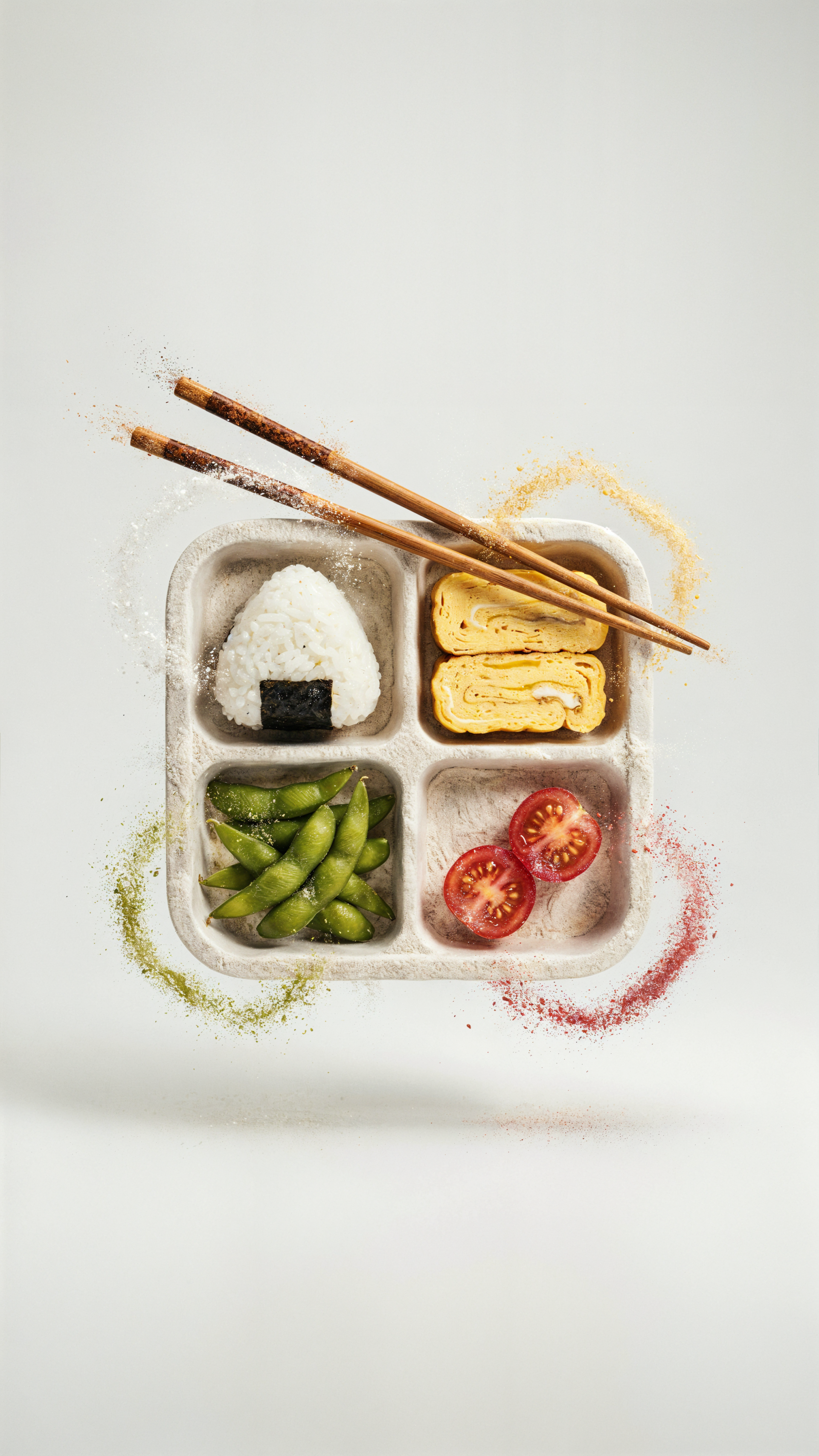 iPhone wallpaper of a bento box: rice onigiri, tamagoyaki, edamame and cherry tomatoes in a divided lunchbox, chopsticks resting atop.
