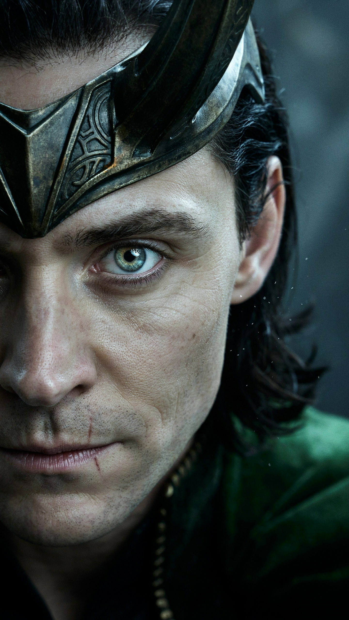 Close-up portrait of Loki (Marvel Comics) in a horned helmet, intense green-eyed stare and dark hair, vertical iPhone wallpaper.
