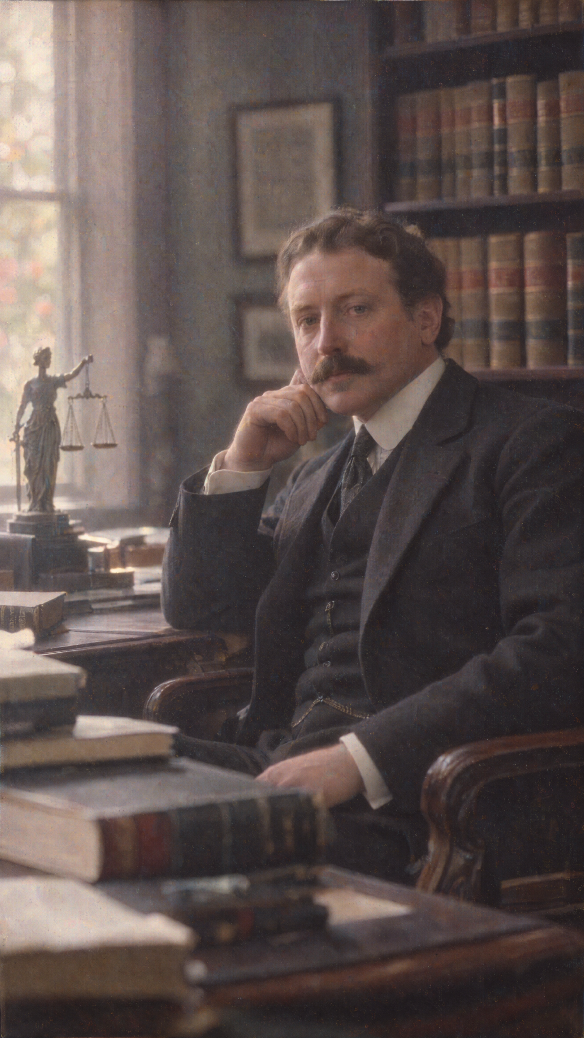 Phone wallpaper of a thoughtful lawyer in a suit seated among books in a library