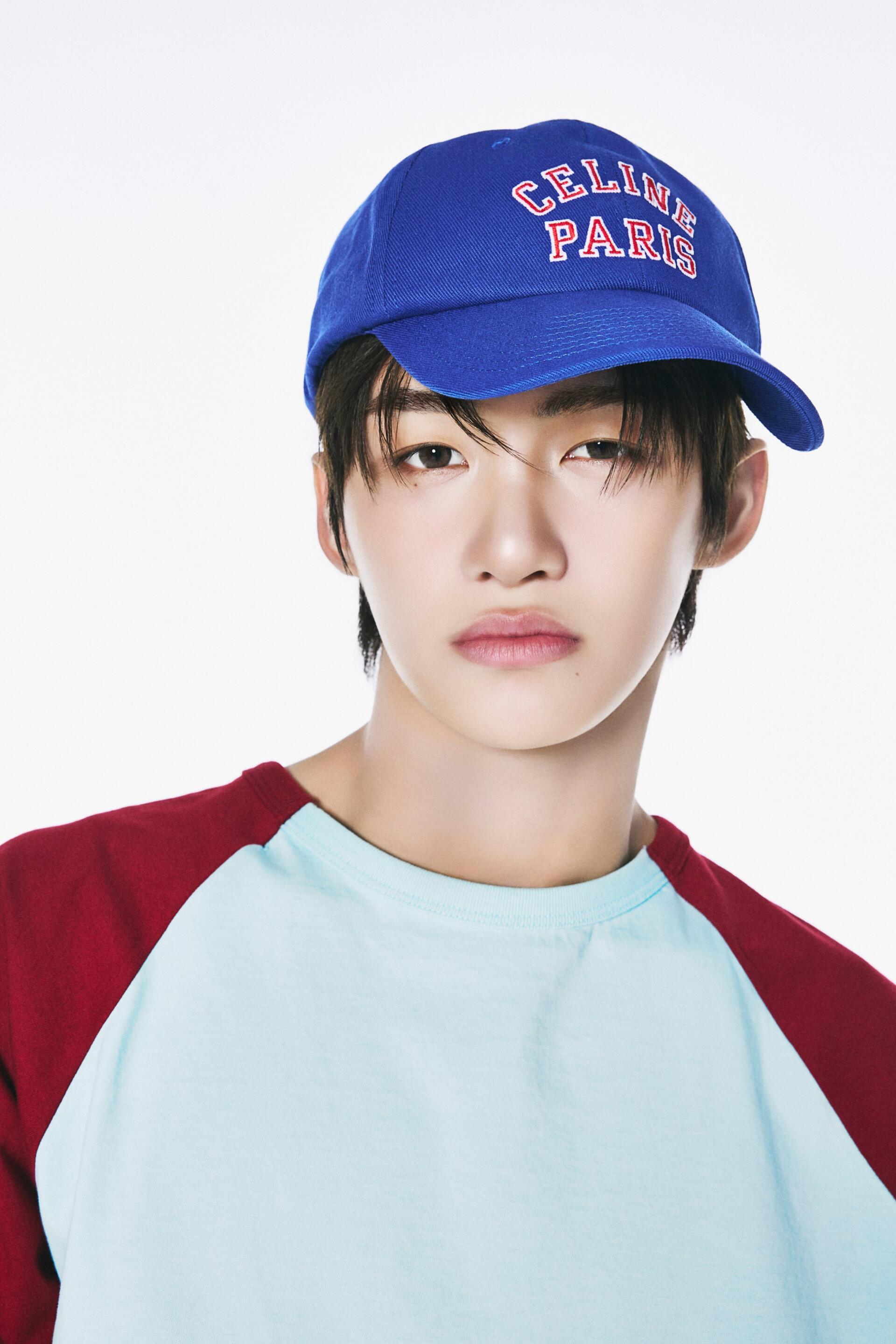 TWS Jihoon portrait iPhone wallpaper featuring a blue CELINE PARIS cap and casual red-and-blue shirt against a clean white background.