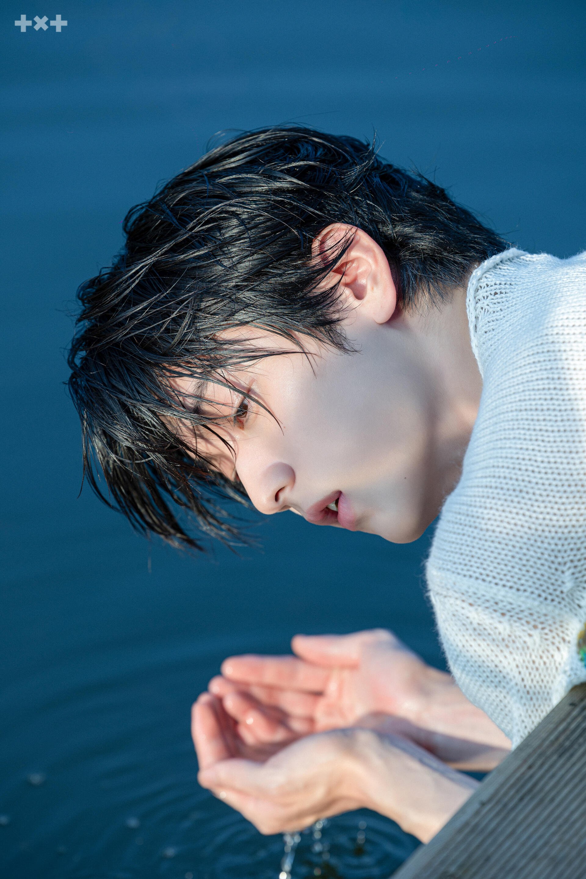 TXT Perfect Storm portrait of a Tomorrow X Together man leaning over blue water, phone wallpaper