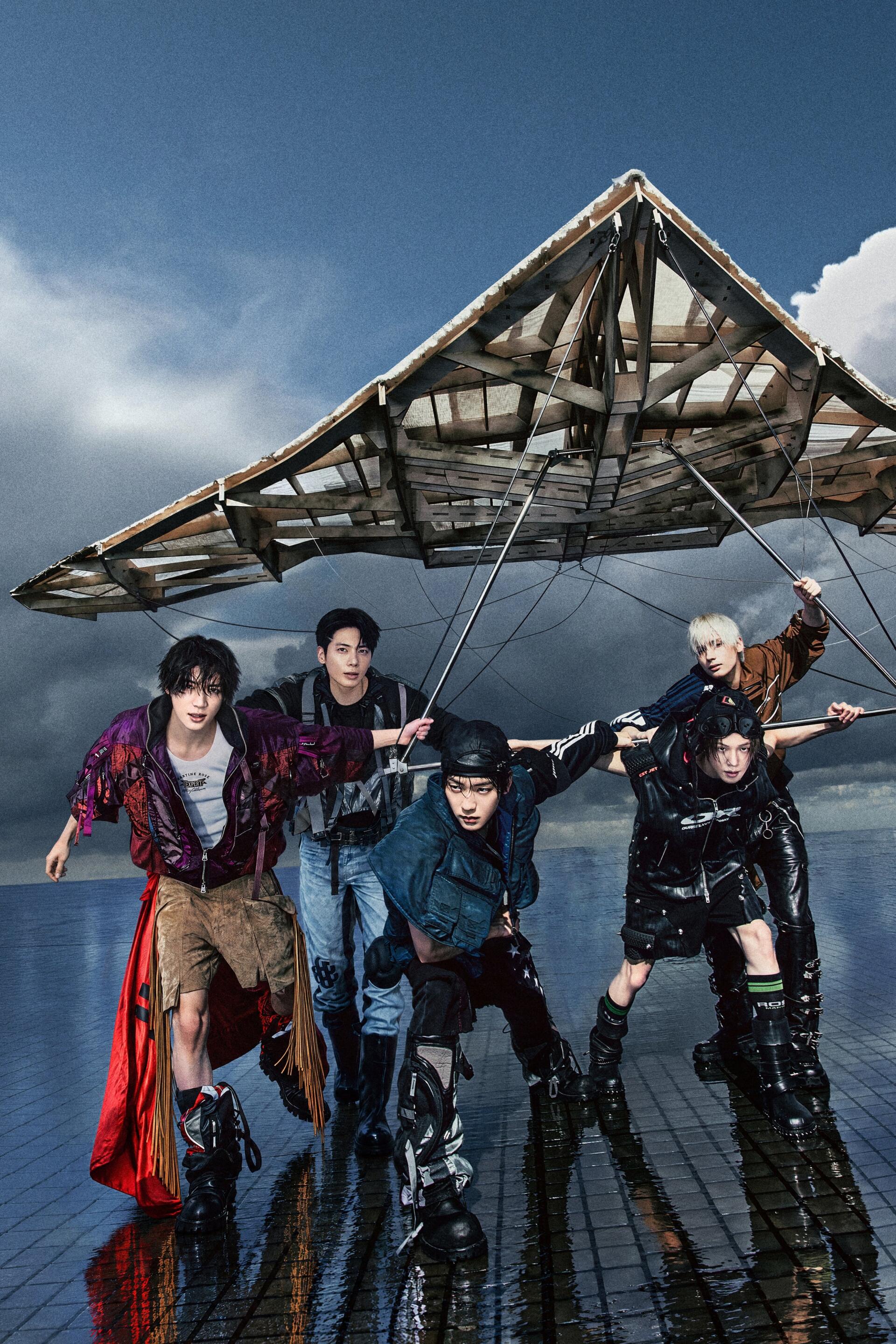 TXT models pose beneath a wrecked aircraft wing in stormy fashion imagery for the Perfect Storm “Ride the Storm” iPhone wallpaper.