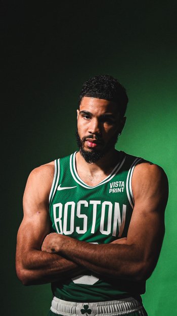 Phone wallpaper featuring a Boston Celtics player in a green jersey, confidently standing with his arms crossed against a dark green background.