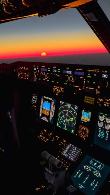An airplane cockpit captures a vibrant sunset, illuminating the controls with warm colors, creating an inspiring phone wallpaper that evokes a sense of adventure and tranquility.