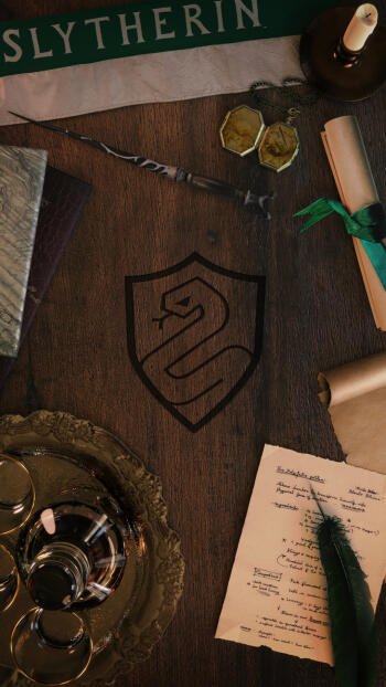 A stylish phone wallpaper featuring the Slytherin crest on a wooden table, surrounded by books, scrolls, and potion tools, perfect for Harry Potter fans.