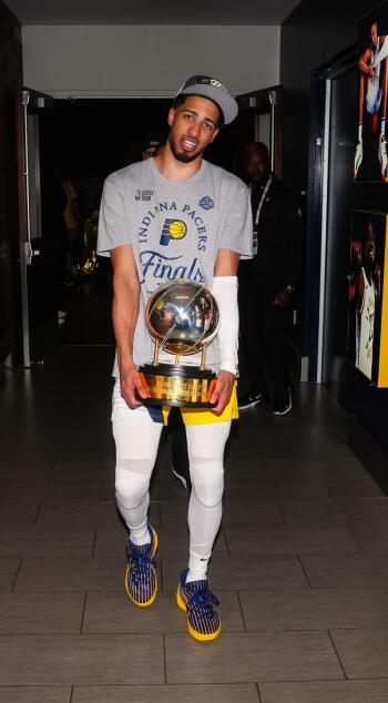 Tyrese Haliburton of the Indiana Pacers holds a championship trophy, wearing a Finals shirt and cap, captured in a celebratory moment suited as a basketball NBA phone wallpaper.