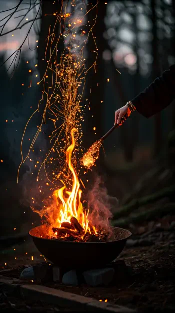 Phone wallpaper showing a fire spell with bright sparks and flames rising from a bowl, set against a dark, blurred forest background, fitting both iPhone and Android screens.