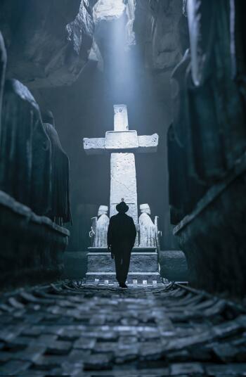 iPhone/Android phone wallpaper: silhouette of Indiana Jones walking toward a large stone cross altar in a dim cavern, artwork from the video game Indiana Jones and the Great Circle.