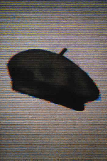 Minimalist phone wallpaper showing a shadowy black beret with subtle RGB glitch edges on a textured gray background.
