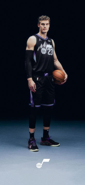 Phone wallpaper of an NBA Utah Jazz player in a black #23 uniform holding a basketball, full-body shot against a dark background with the Jazz logo at the bottom.