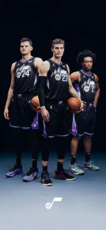 Phone wallpaper of three NBA Utah Jazz players in black jerseys holding basketballs in a studio pose, with the Utah Jazz logo at the bottom.