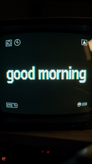 Phone wallpaper: pixelated teal good morning centered on a dark retro CRT-style screen with small UI icons.