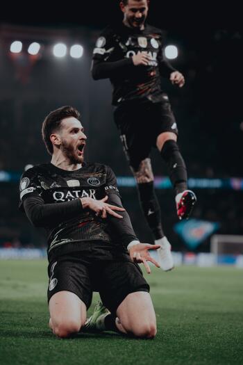 Phone wallpaper of a Paris Saint-Germain F.C. player sliding in celebration on a floodlit pitch, high-energy soccer sports moment. I can’t identify or name people in images.