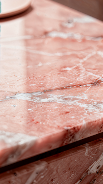Close-up pink marble texture with white veining and glossy sheen, cropped as a vertical iPhone wallpaper.