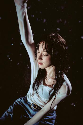 Yuqi of (G)I-DLE poses with one arm raised against a dark, atmospheric background in this phone wallpaper.