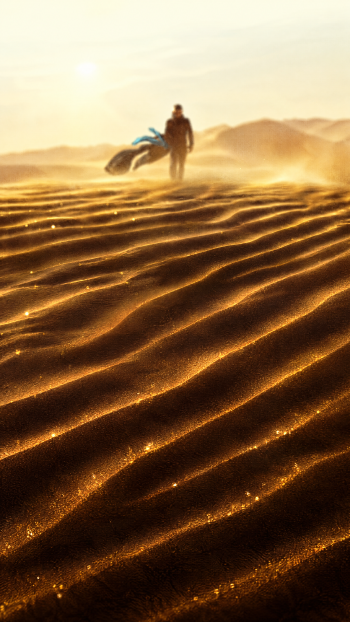 Dune: Part Three iPhone wallpaper featuring a lone figure crossing glowing, rippled desert sand dunes.