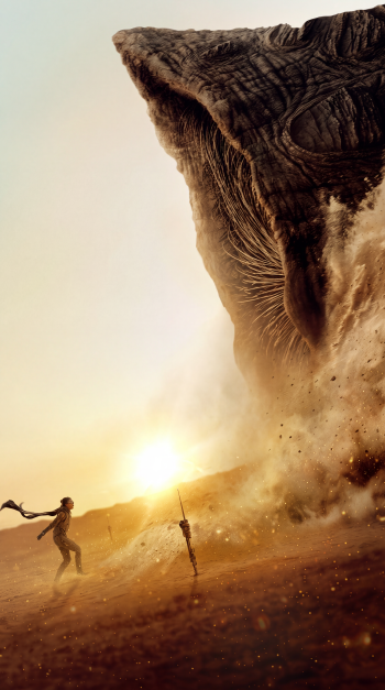 Dune: Part Three iPhone wallpaper featuring a giant sandworm monster towering over a lone figure in a sunlit desert.