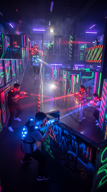 Laser tag players battle in a neon-lit arena, captured as a vibrant iPhone wallpaper.