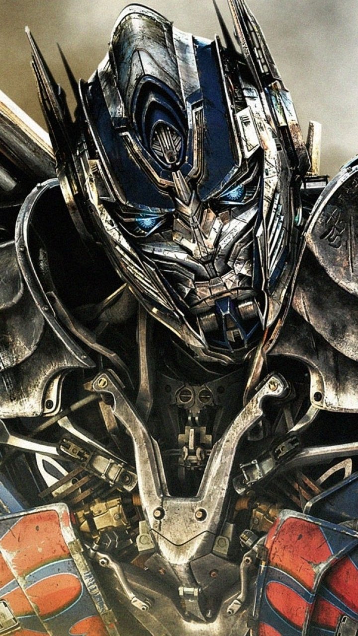 Close-up of Optimus Prime from Transformers: Age of Extinction with metallic faceplate, glowing blue eyes and armored chest, styled as a phone wallpaper.
