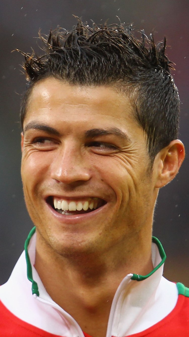 Close-up of Cristiano Ronaldo smiling, designed as a vibrant sports-themed phone wallpaper for iPhone and Android devices.