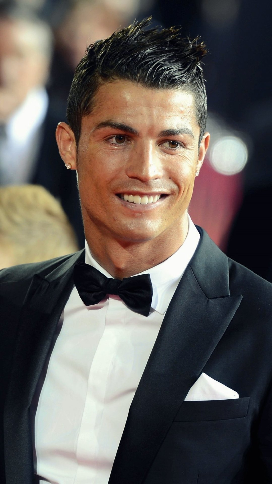 Portrait of Cristiano Ronaldo in a black tuxedo, designed as a sports-themed phone wallpaper for both iPhone and Android devices.