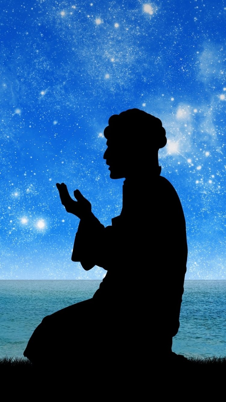 Silhouette of a person praying under a starry night sky with a crescent moon, designed as a religious-themed phone wallpaper for iPhone and Android.
