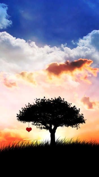 Artistic phone wallpaper showing a silhouetted tree on a grassy hill under a vivid cloud-filled sky, two small hearts by the trunk hinting at love and a couple.